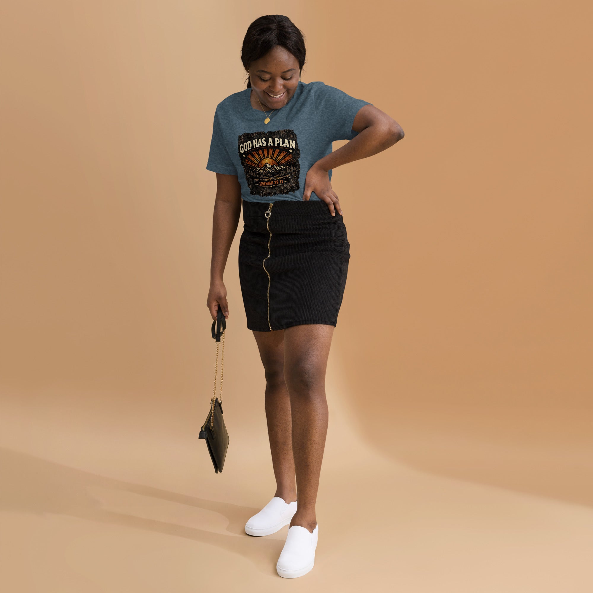 Woman wearing a blue t-shirt with God Has A Plan and graphics, black skirt, and white shoes on a beige background