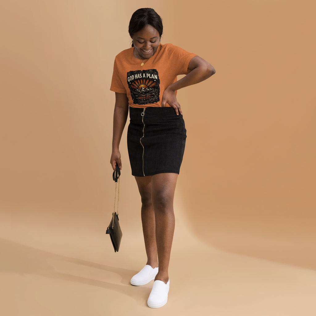 Woman wearing an orange t-shirt with a God Has A Plan graphic design on a beige background