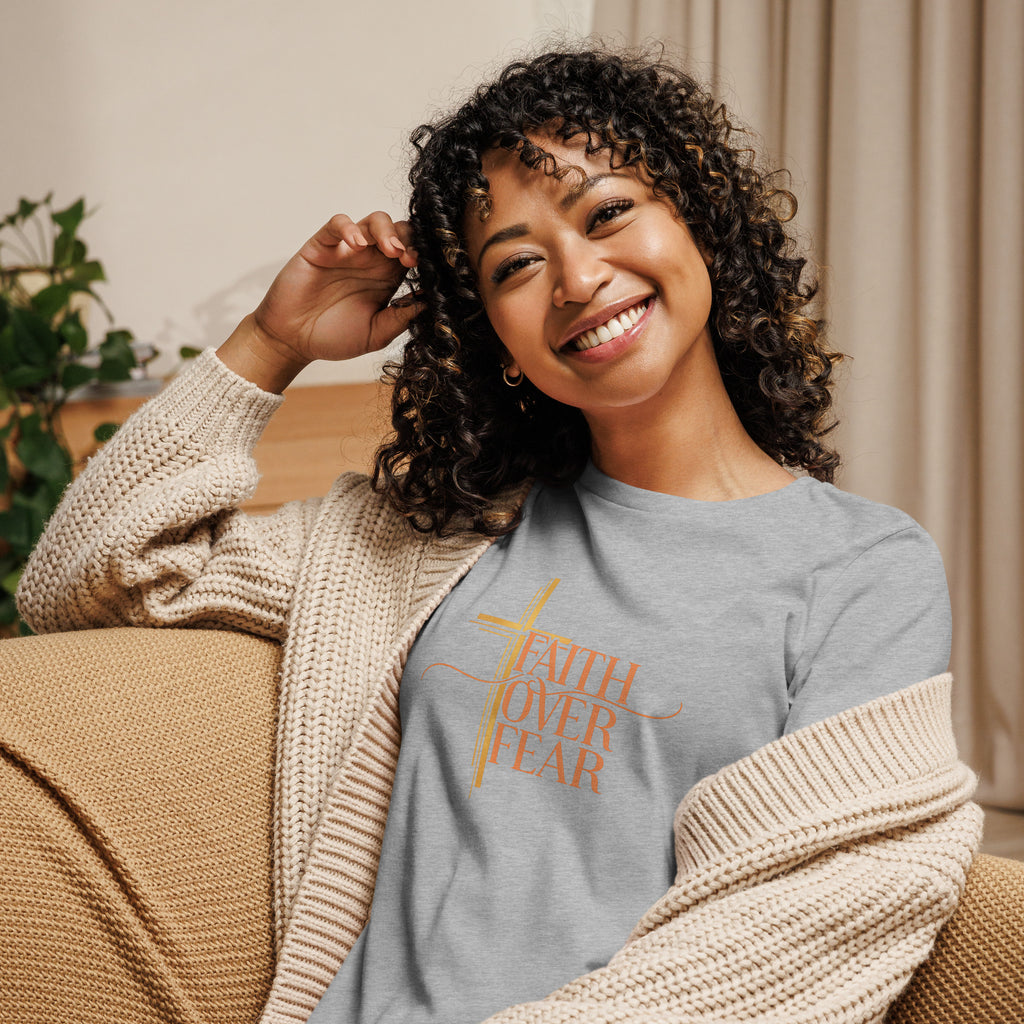 Woman wearing a gray sweatshirt with 'Faith Over Fear' text, sitting on a couch.