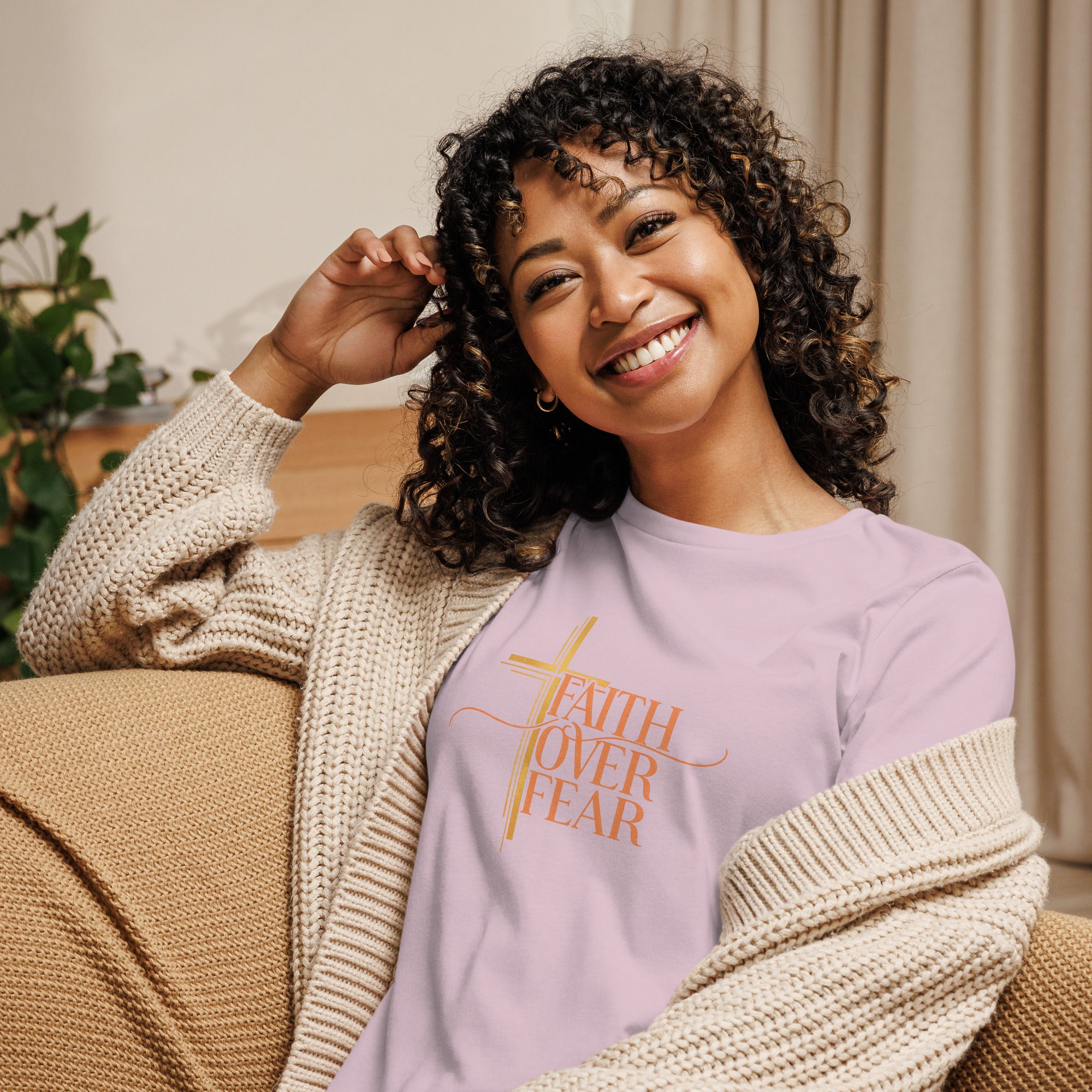 Woman wearing a purple sweatshirt with 'Faith Over Fear' text, sitting on a couch.